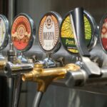 Close-up of craft beer taps with diverse labels in a bar setting. Ideal for beverages and brewery themes.